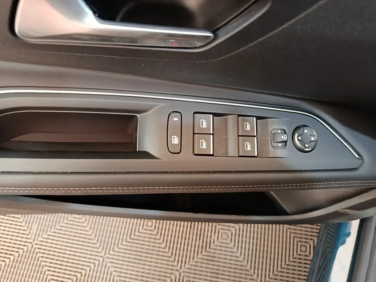 Vue rapprochée de la commande des vitres et rétroviseurs sur la porte côté conducteur d’un Peugeot 3008 bleu.
