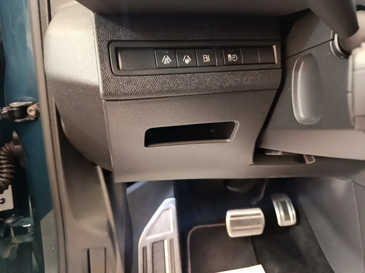 Vue intérieure côté conducteur du Peugeot 3008 bleu, montrant les pédales sport en aluminium et les commandes sous le tableau de bord.