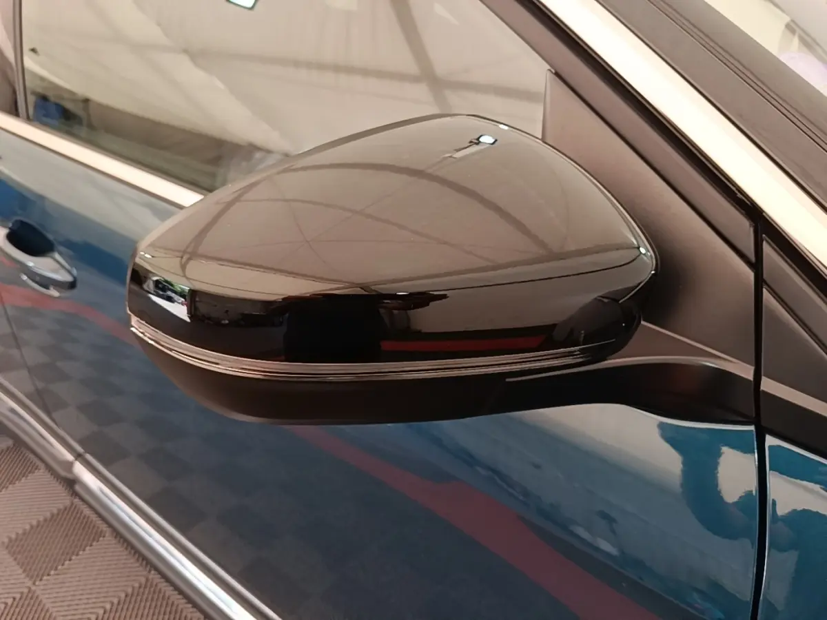 Rétroviseur latéral droit noir brillant sur Peugeot 3008 bleu, vue rapprochée côté porte avant.
