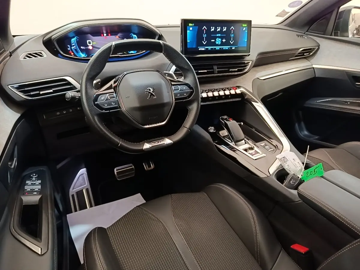Intérieur du Peugeot 3008 hybride 2022 vu côté conducteur, volant cuir, tableau de bord digital et console centrale moderne.