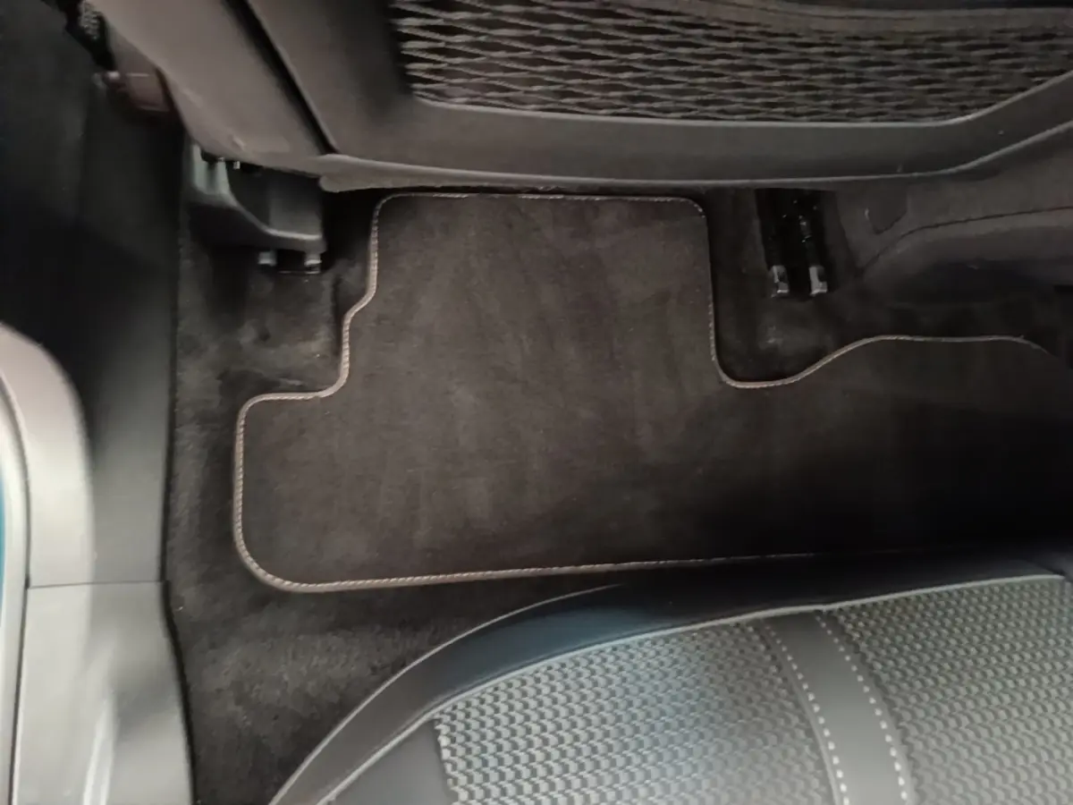 Vue rapprochée du tapis de sol noir et de la partie inférieure du siège arrière dans un Peugeot 3008 bleu hybride rechargeable.