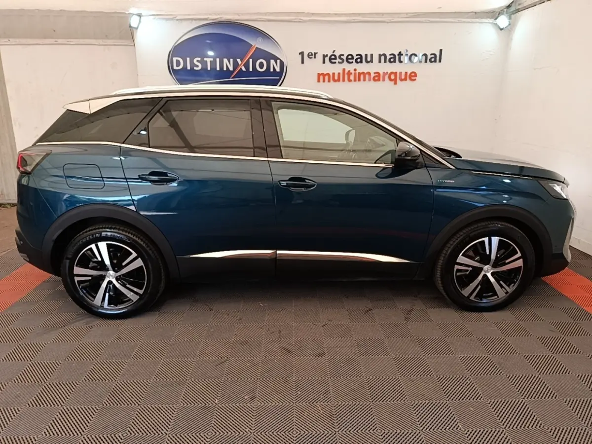 Profil latéral gauche d’un Peugeot 3008 hybride rechargeable bleu avec jantes alliage et toit blanc en showroom.