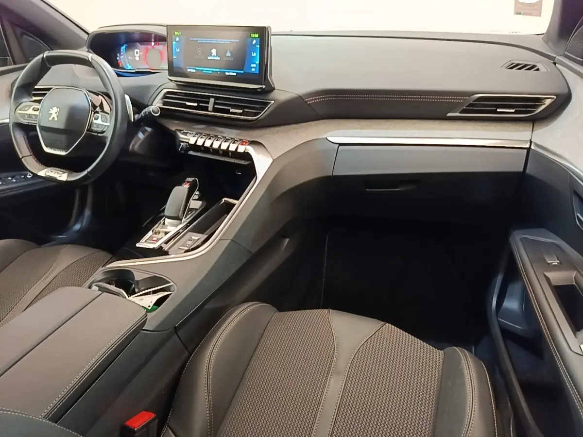 Intérieur Peugeot 3008 hybride 2022 vu côté passager, tableau de bord moderne avec écran tactile central et volant compact.