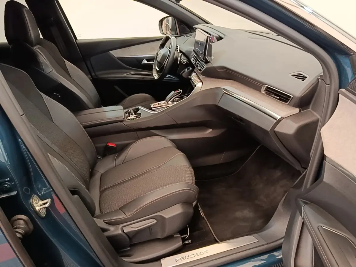 Vue intérieure côté passager avant d’un Peugeot 3008 bleu avec sièges noirs et tableau de bord moderne.