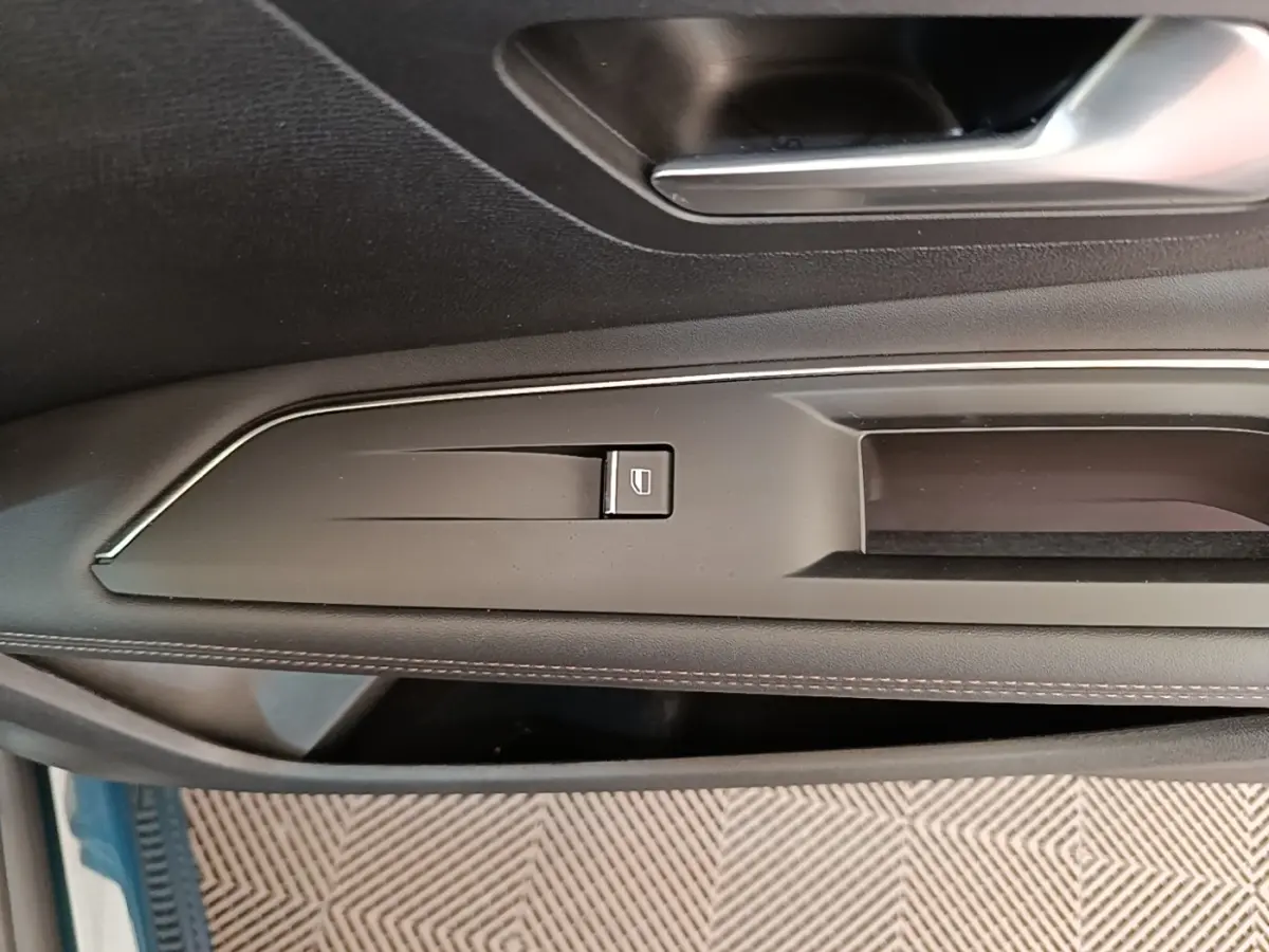 Gros plan sur la commande de lève-vitre côté gauche de la porte intérieure noire du Peugeot 3008 hybride bleu.