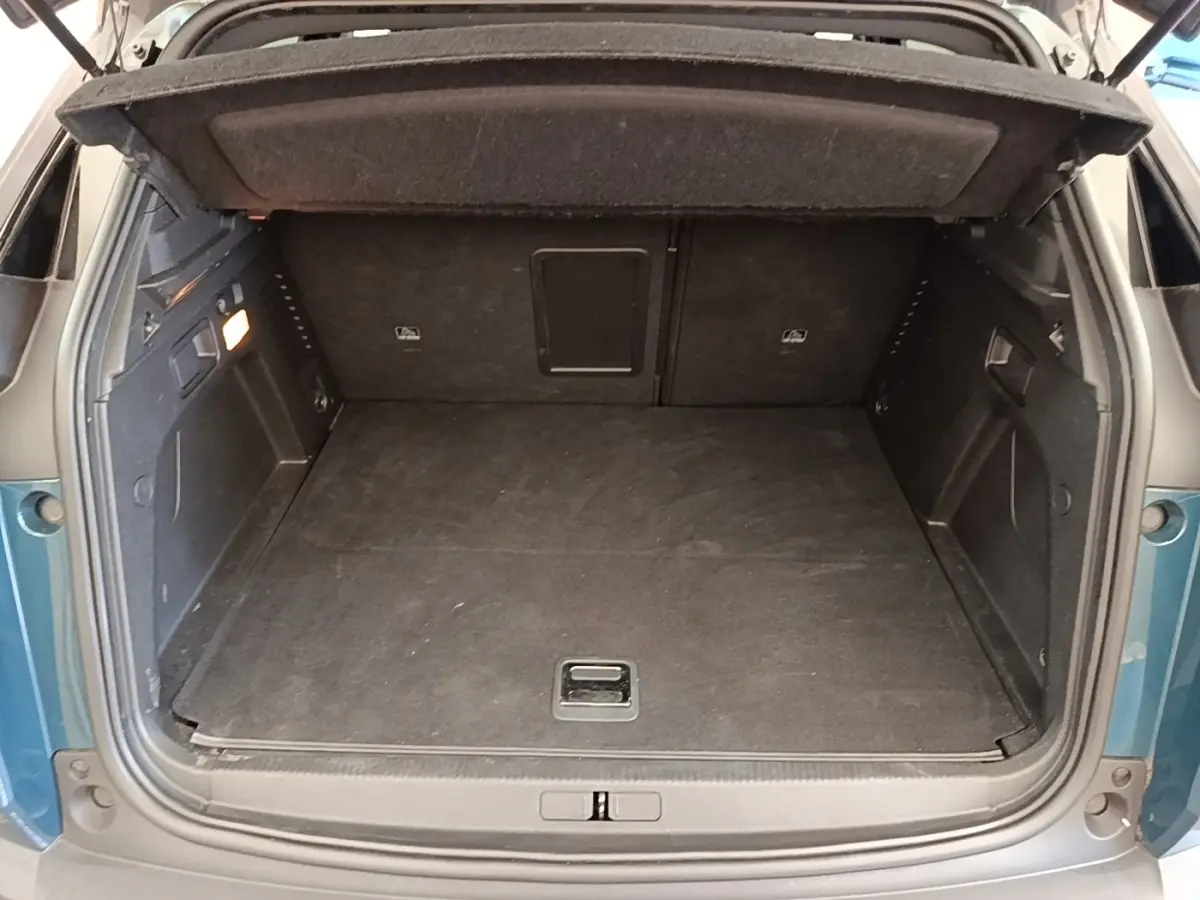 Coffre ouvert vu de l'arrière d'un Peugeot 3008 bleu hybride rechargeable, avec plancher plat et intérieur noir.
