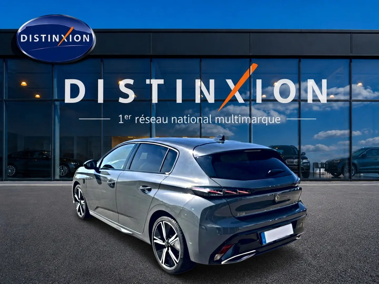 Peugeot 308 gris 3/4 arrière droit, jantes alu et feux arrière LED, devant vitrine Distinxion.
