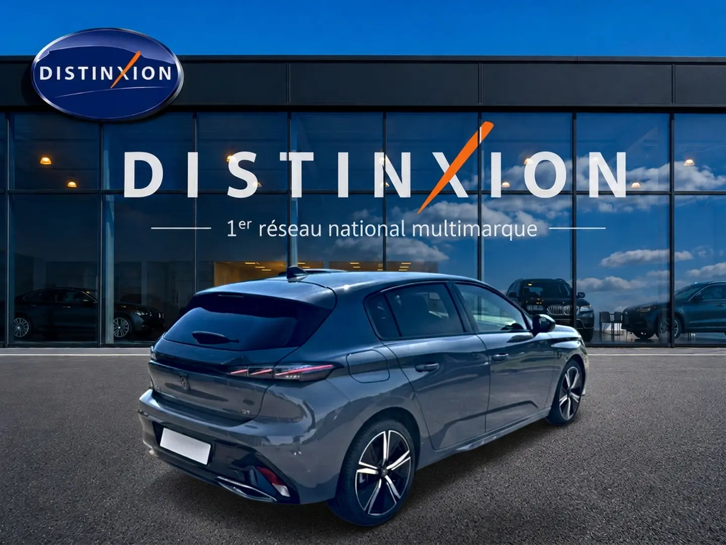 Peugeot 308 1.2 hybrid 145 GT gris en 3/4 arrière droit devant une vitrine Distinxion.