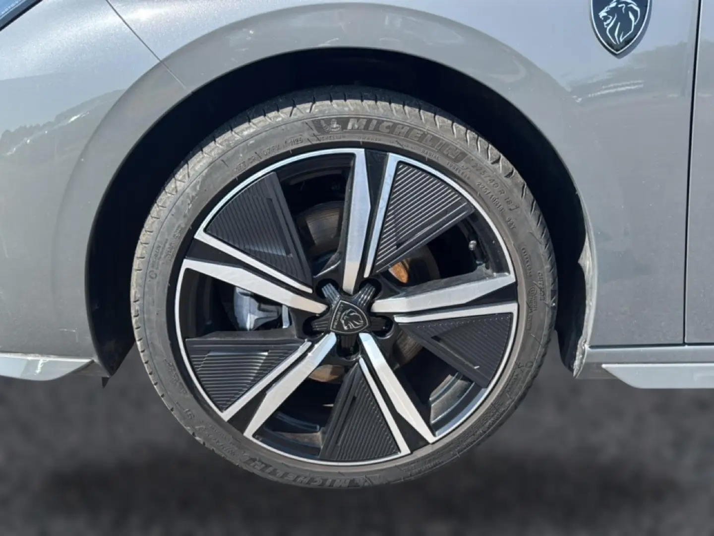 Gros plan sur la roue avant droite grise d'une Peugeot 308 1.2 hybrid 145 GT avec jante alu noire et argentée au design moderne.
