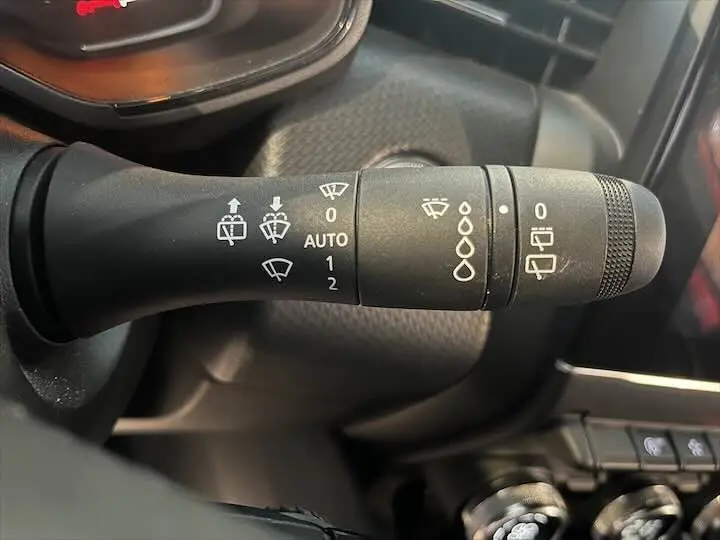 Gros plan sur la commande des essuie-glaces dans l'habitacle d'une Renault Clio V rouge flamme métal.