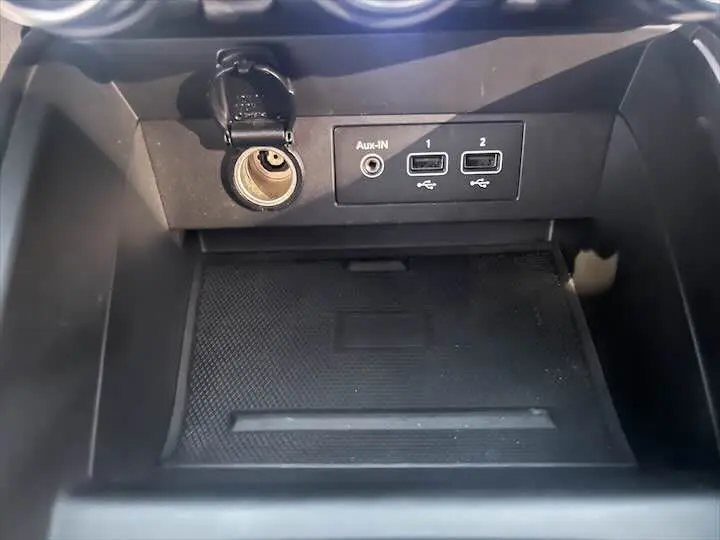 Prise allume-cigare ouverte avec ports USB et entrée Aux dans la console centrale de la Renault Clio V rouge flamme.