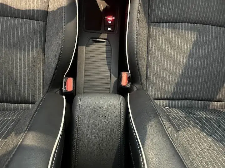 Vue rapprochée de la console centrale et des sièges avant en tissu gris rayé avec surpiqûres blanches sur une Renault Clio V.