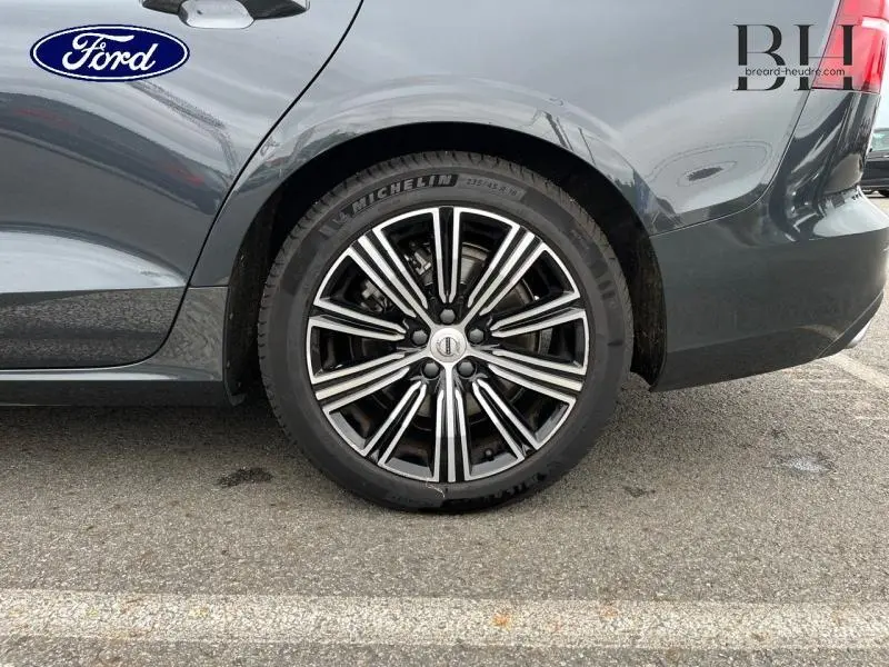 Gros plan sur la roue arrière droite d'une Volvo V60 T8 gris Savile métallisé avec jante alu noire et argentée.