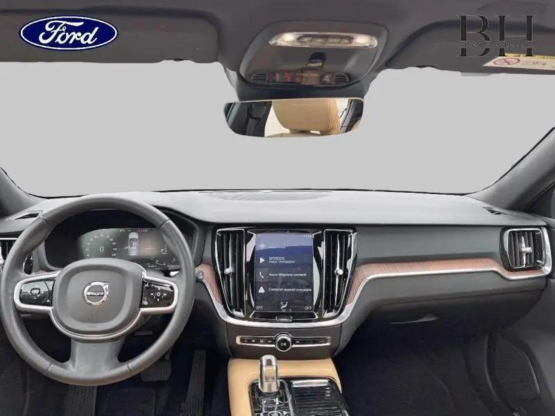 Vue intérieure frontale du tableau de bord du Volvo V60 gris Savile, avec volant cuir et écran tactile central.