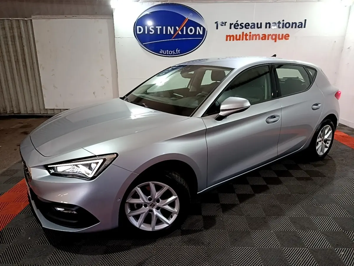 SEAT LEON gris clair vue 3/4 avant droit en intérieur avec jantes alliage et phares LED allumés