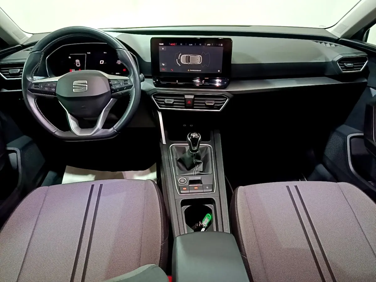 Intérieur de la SEAT Leon 2023, vue frontale du tableau de bord avec écran tactile et volant multifonctions noir.