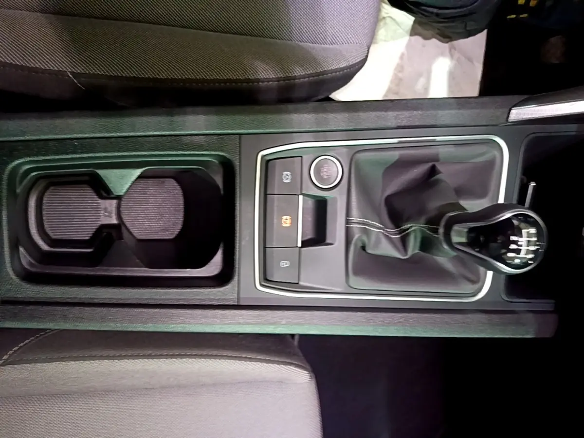 Vue plongeante sur la console centrale grise du SEAT LEON 2023, avec levier de vitesse manuel et porte-gobelets.
