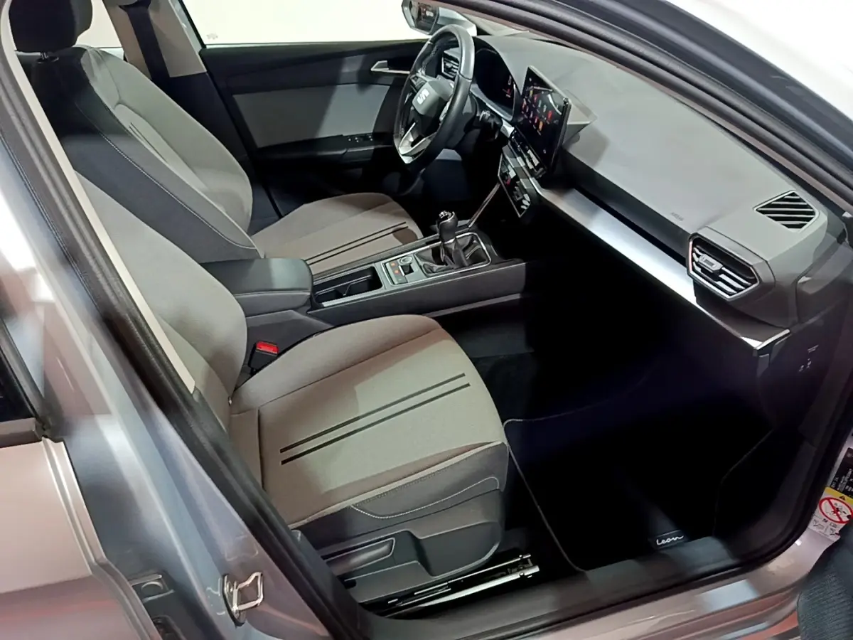 Intérieur côté conducteur du SEAT Leon gris clair 2023, avec tableau de bord moderne et écran tactile central.