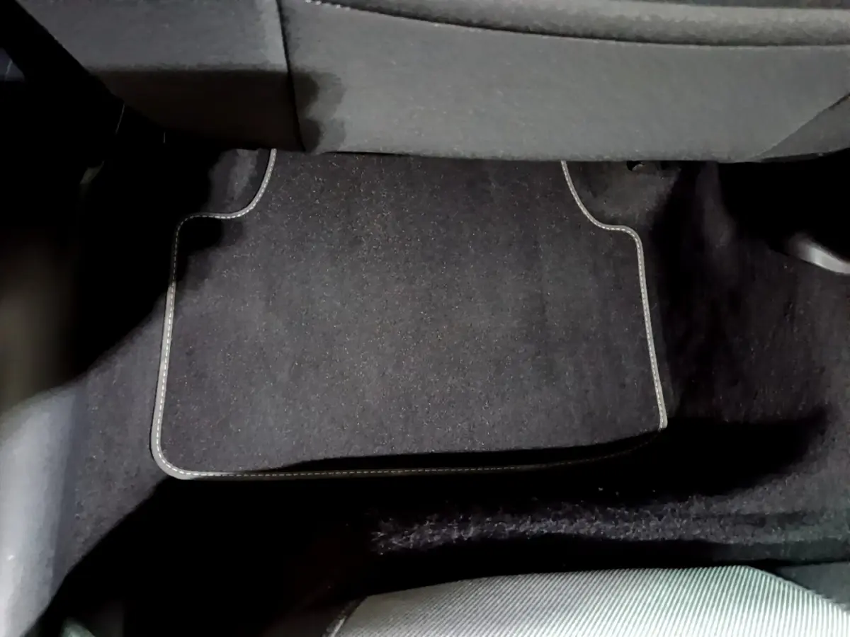 Tapis de sol noir avec surpiqûres blanches sous le siège arrière d'une SEAT Leon gris clair 2023