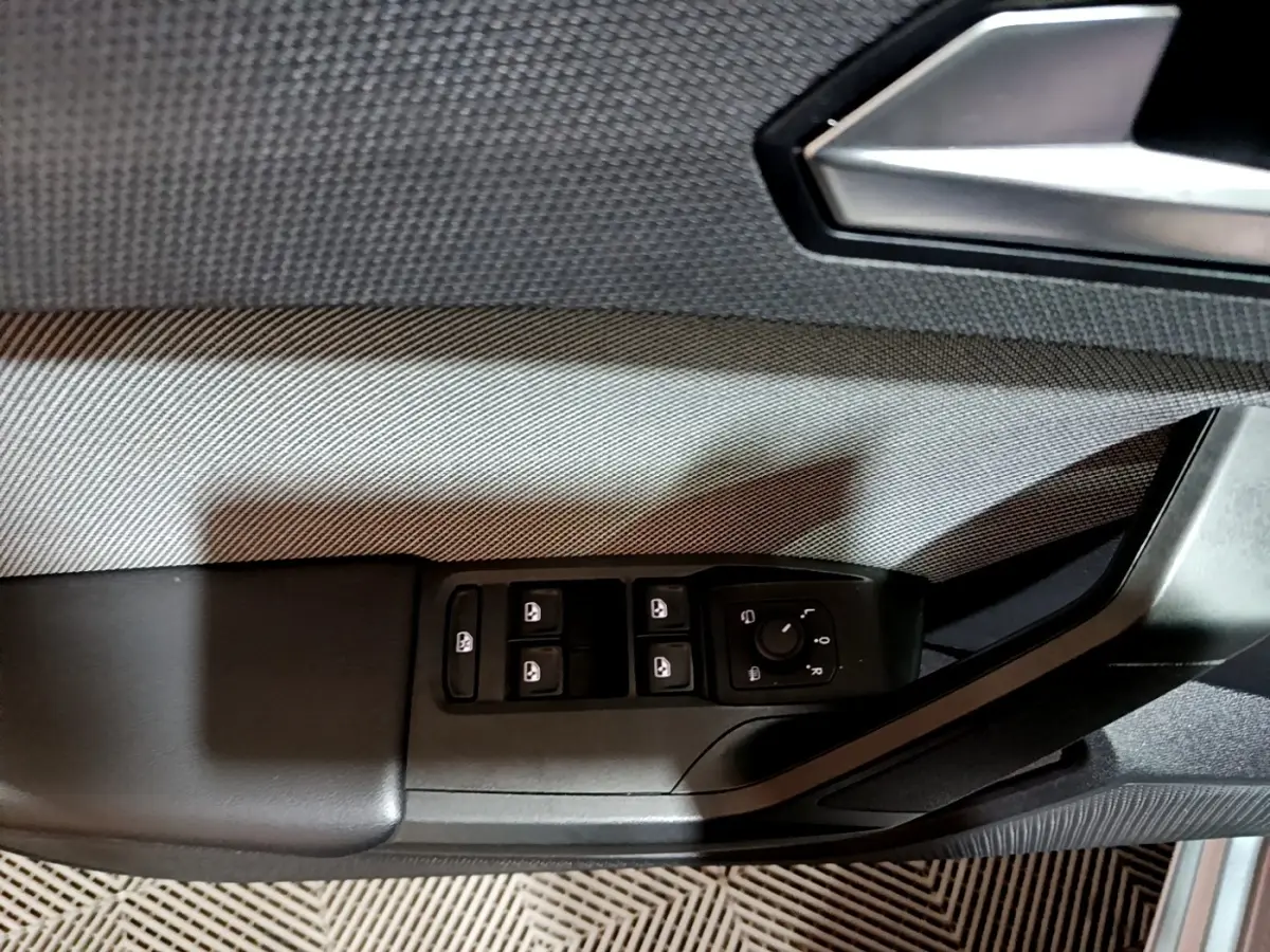 Gros plan sur la commande des vitres et rétroviseurs côté conducteur d'une SEAT Leon gris clair 2023.