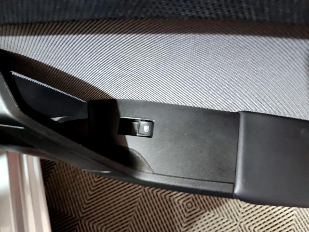 Gros plan sur le bouton de verrouillage des portes sur la garniture intérieure noire côté conducteur d'une SEAT Leon gris clair.