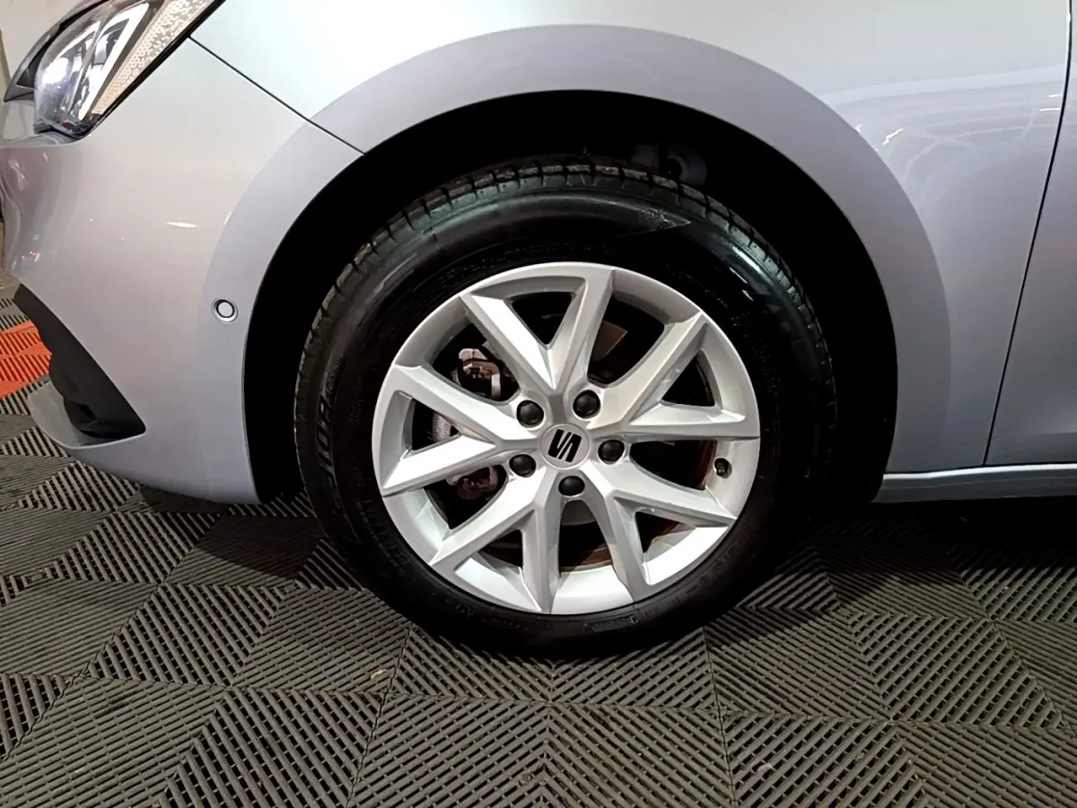 Gros plan sur la roue avant gauche gris clair d'une SEAT LEON 2023 avec jante alliage à 5 branches doubles.