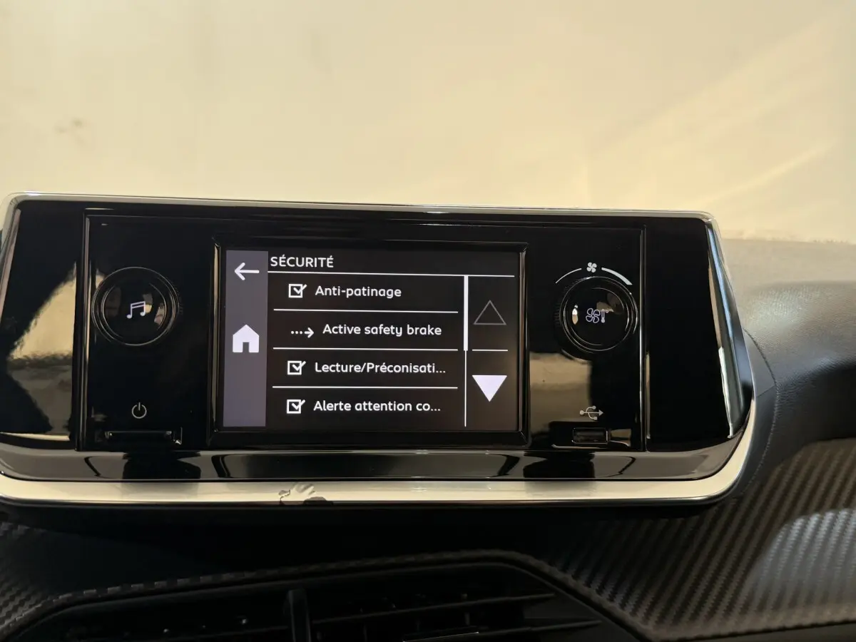 Vue rapprochée de l’écran tactile central noir de la Peugeot 208 PureTech 75 affichant les options de sécurité.