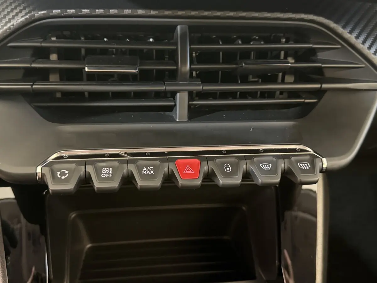 Gros plan sur la rangée de boutons de commande de la climatisation et des alertes dans l’habitacle d’une Peugeot 208 2020.