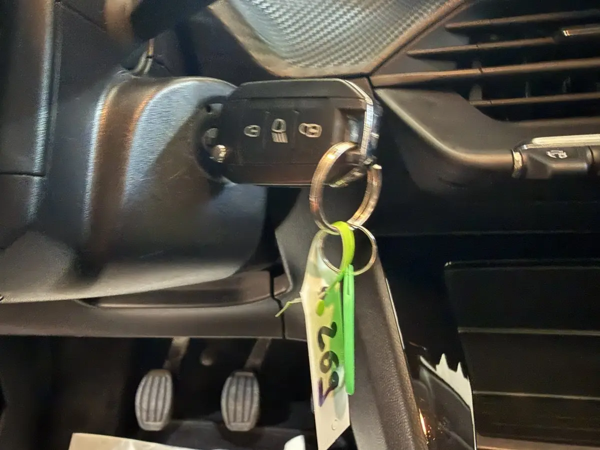 Gros plan sur la clé de contact insérée dans le contacteur d'une Peugeot 208 PureTech 75 S&S Like, intérieur noir.