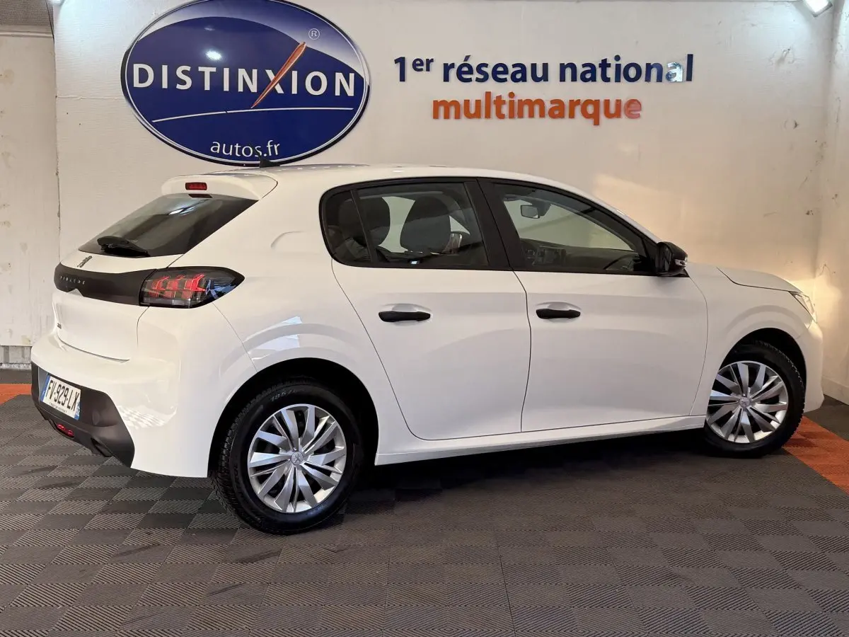 Vue de profil droit d'une Peugeot 208 PureTech 75 S&S Like blanche, avec jantes alliage et feux arrière distinctifs.