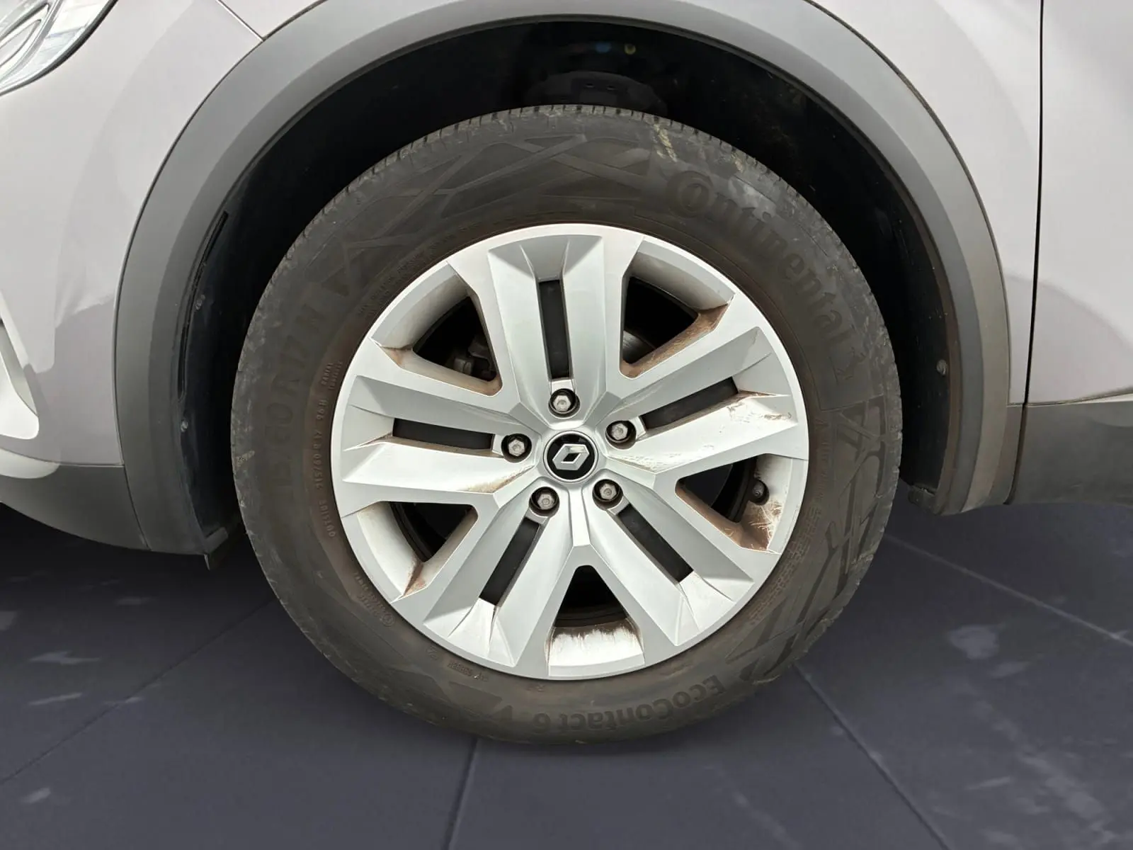 Gros plan sur la roue avant gauche d’un Renault Captur gris Cassiopée avec jante alliage à cinq doubles branches.