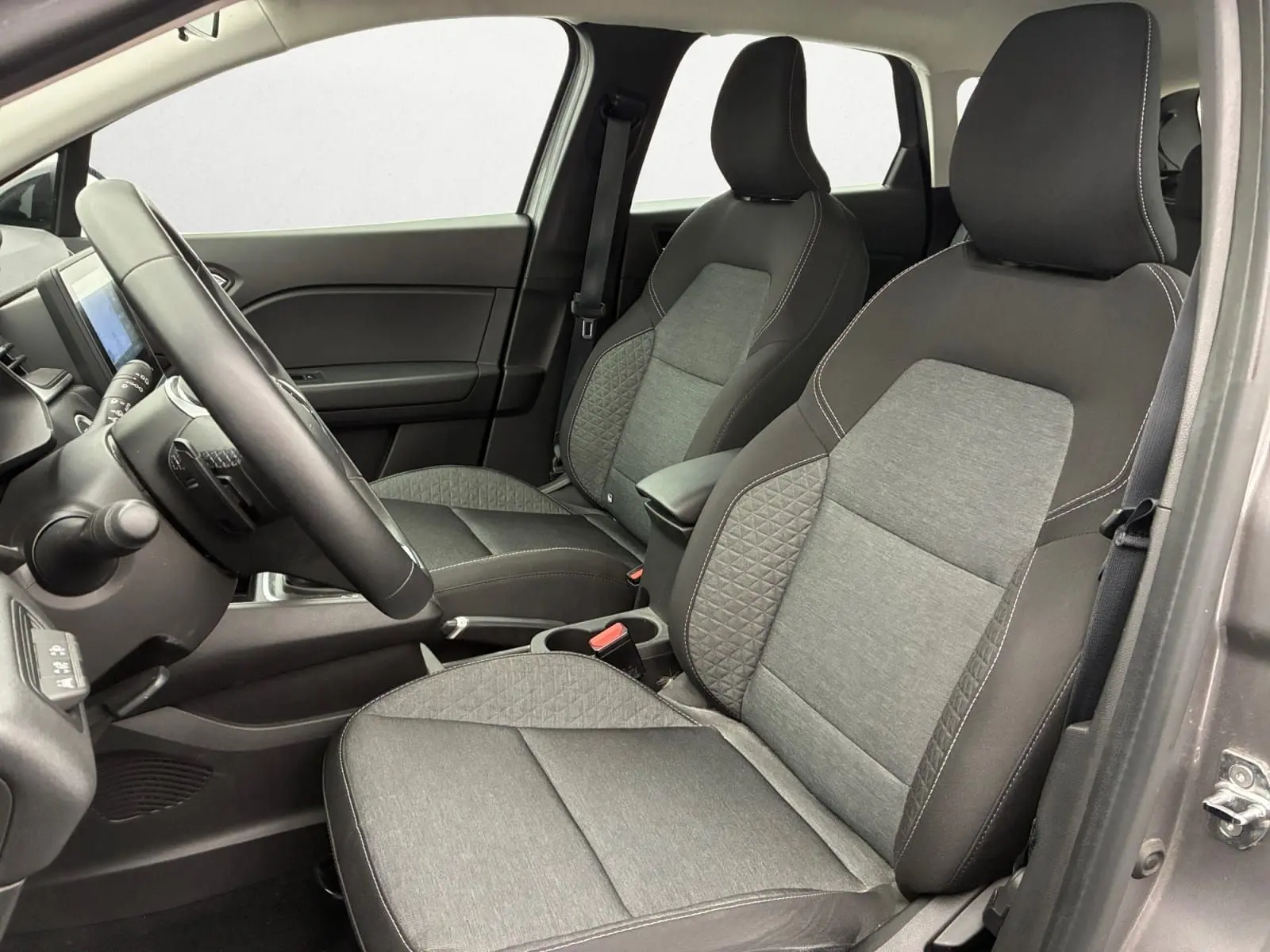 Vue intérieure côté conducteur du Renault Captur 2022 avec sièges tissu noir et gris à surpiqûres blanches.