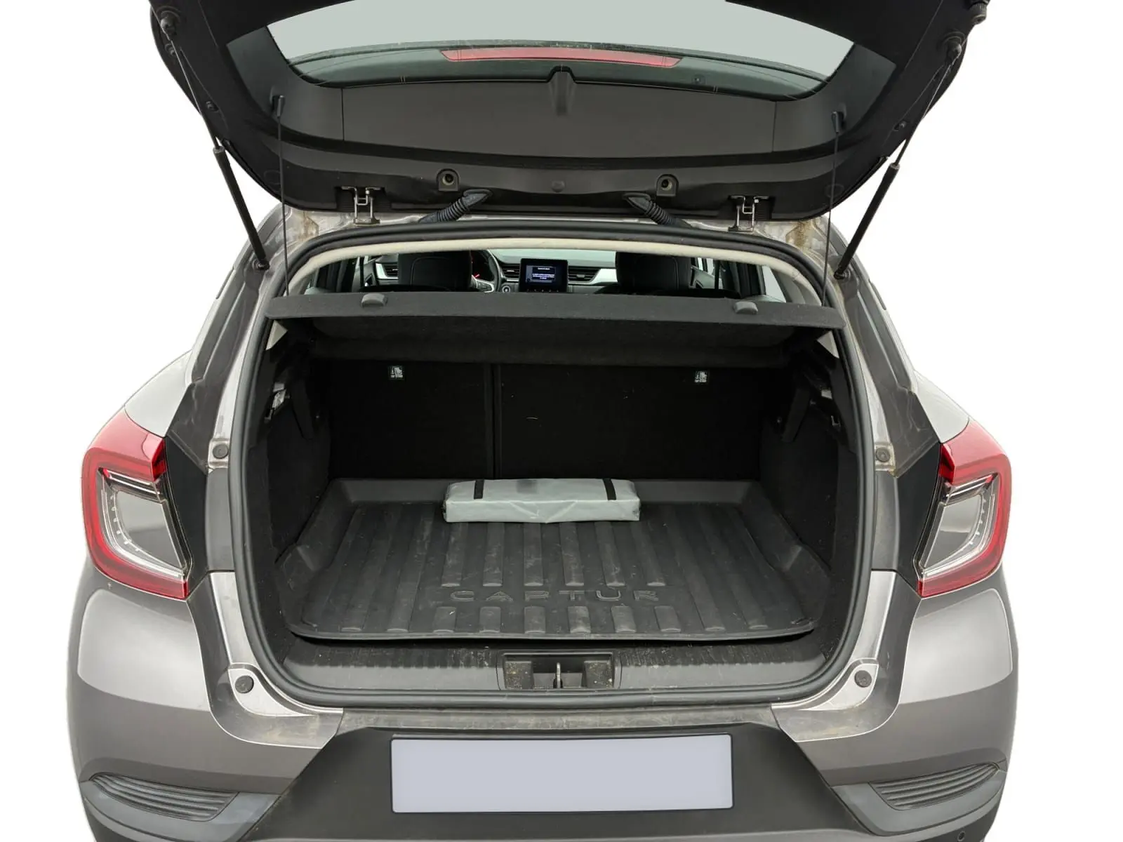 Vue arrière du coffre ouvert d'un Renault Captur gris Cassiopée avec toit noir, montrant le tapis de coffre et l'habitacle.
