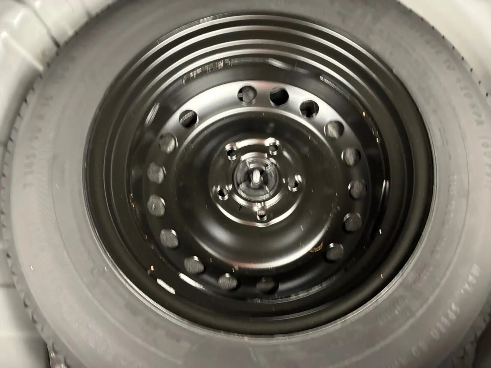 Gros plan sur la roue de secours noire du Renault Captur TCE 140 EDC 21 Business, visible en intérieur coffre.