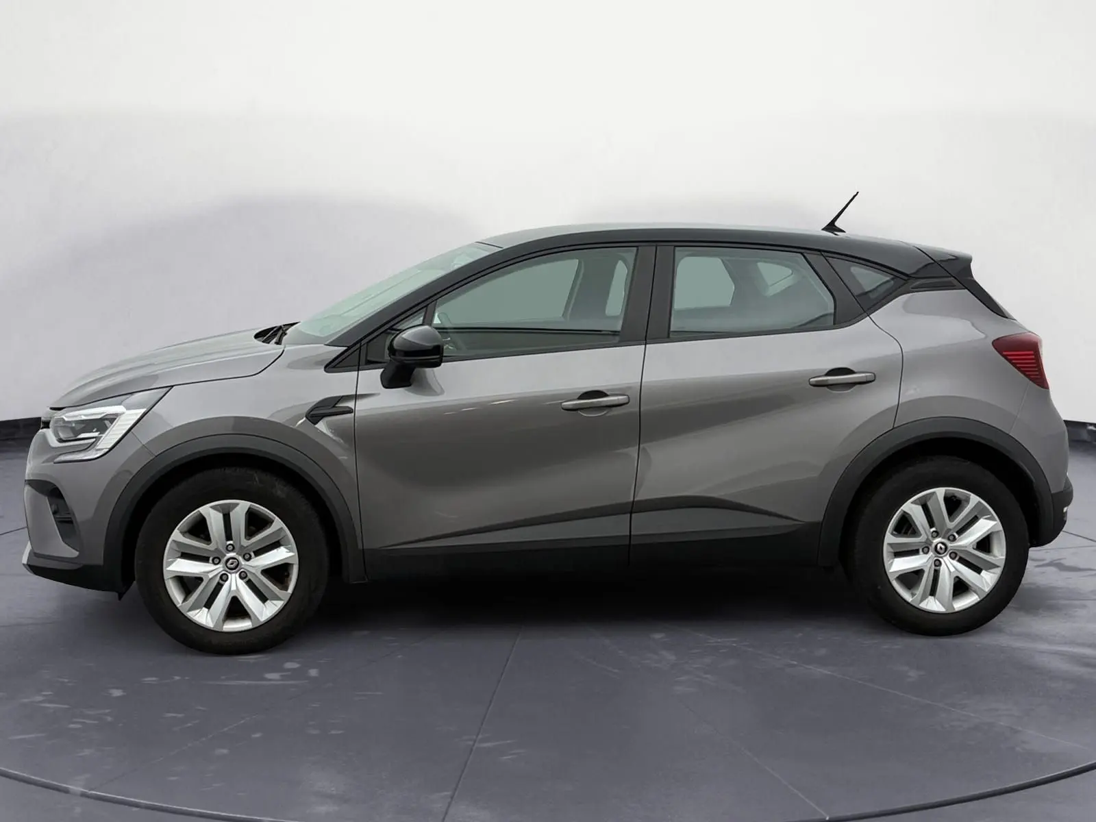 Profil côté gauche du Renault Captur 2022 gris Cassiopée avec toit noir et roue de secours visible.