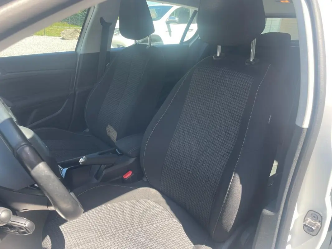 Vue intérieure côté gauche montrant les sièges avant en tissu noir et gris d'une Peugeot 308 blanche 2020.