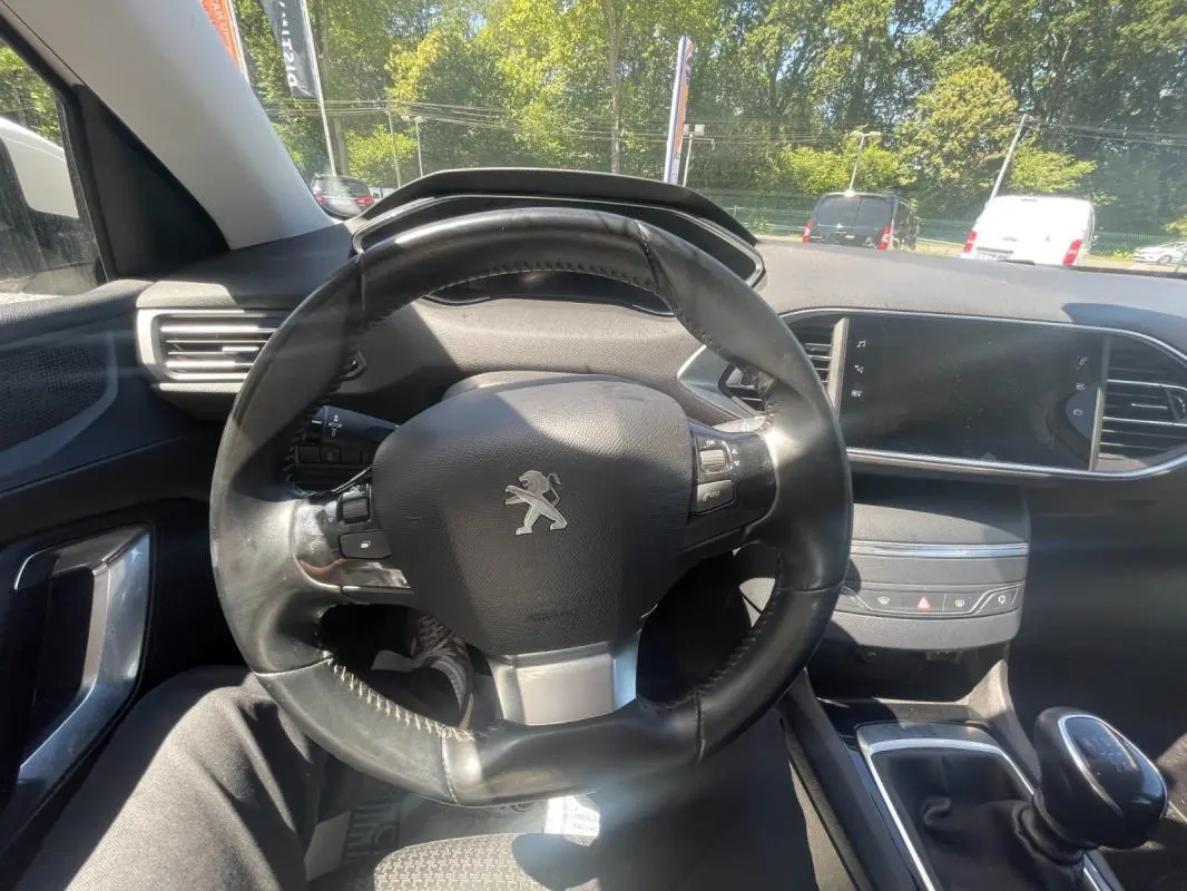 Intérieur de la Peugeot 308 2020 blanc, vue centrée sur le volant et la console avec boîte manuelle visible.