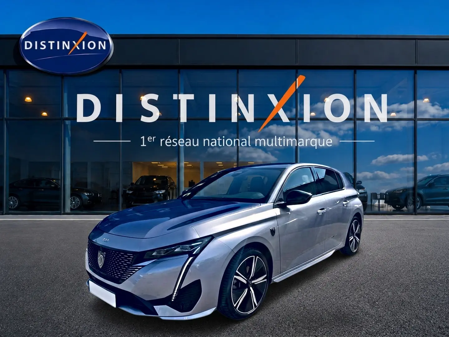 Peugeot 308 gris vue 3/4 avant droit, avec jantes alliage et phares LED distinctifs, devant showroom Distinxion.