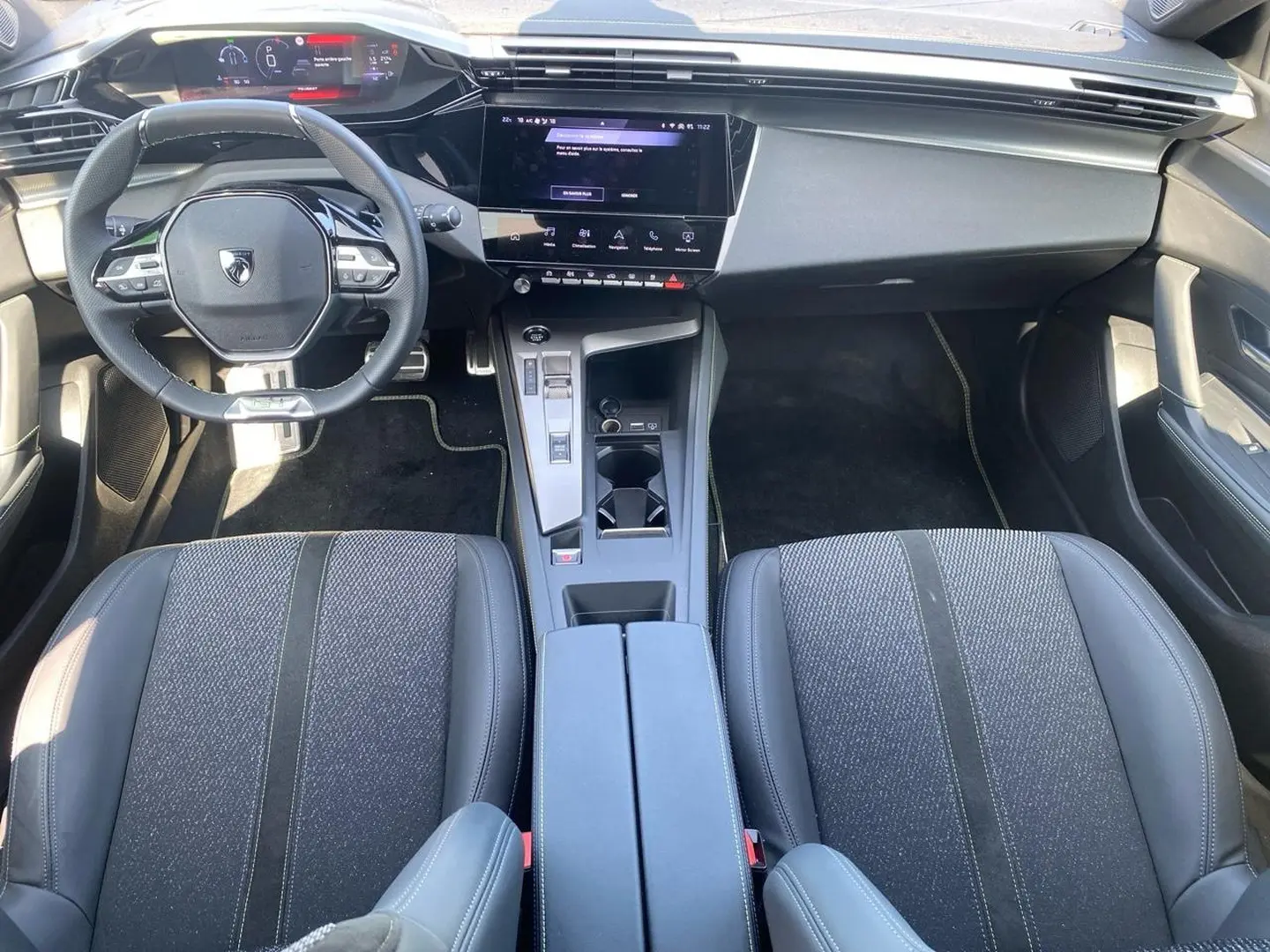 Vue intérieure avant de la Peugeot 308 1.2 hybrid 145 GT e-dcs6 2025, montrant sièges noirs, volant multifonction et écran tactile central.