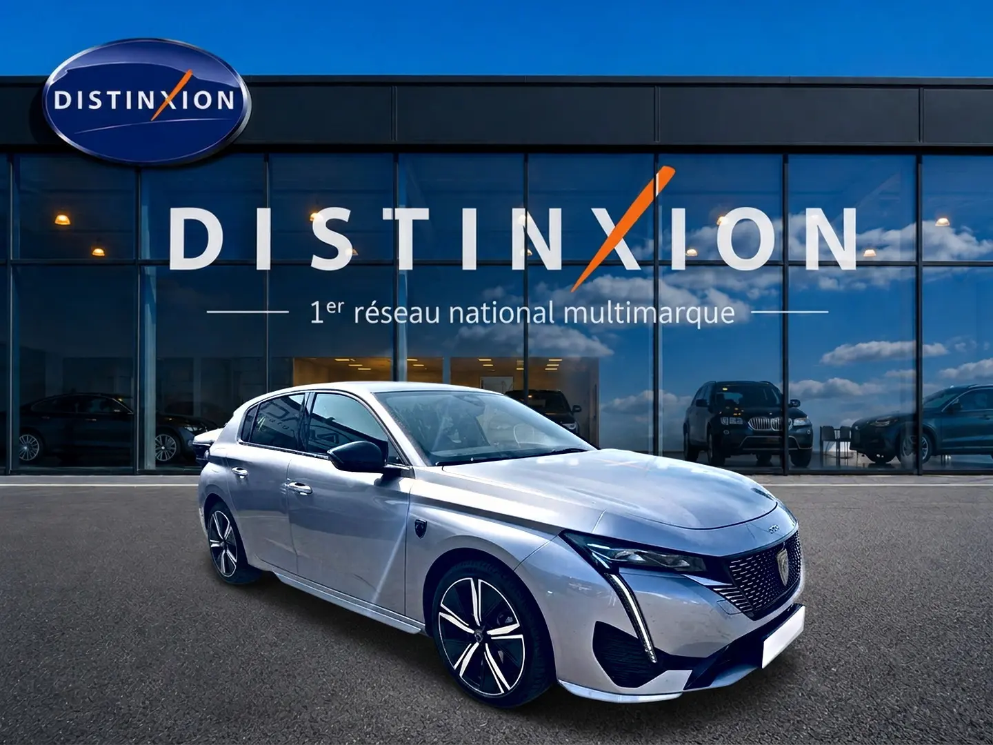 PEUGEOT 308 gris en 3/4 avant droit, avec jantes alu et calandre distinctive, devant showroom Distinxion.