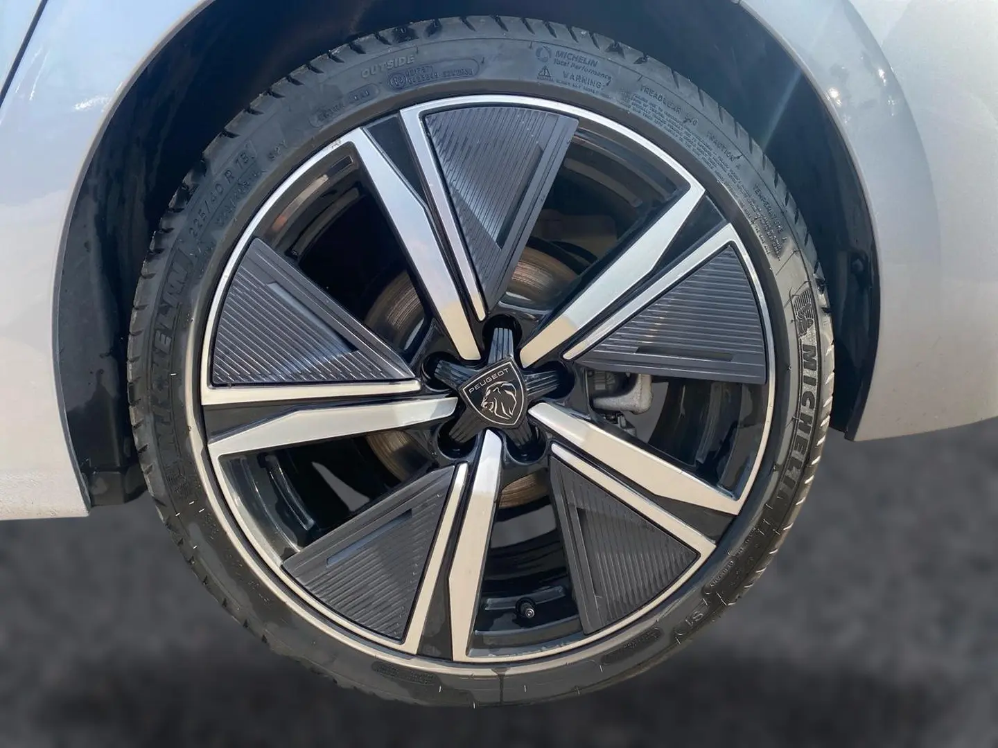 Gros plan sur la jante alu noire et argentée du côté avant gauche d’une Peugeot 308 gris clair.