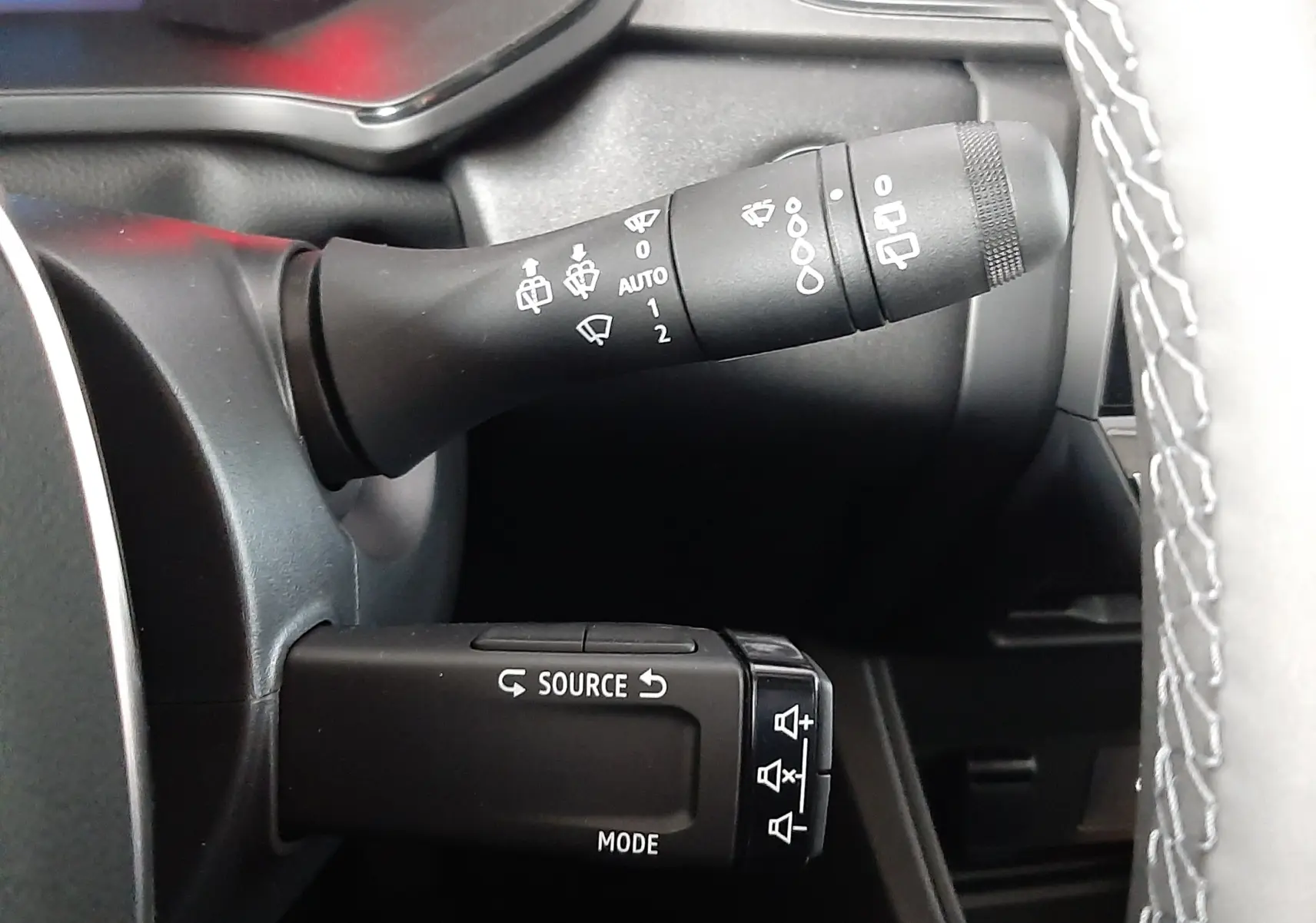 Gros plan sur les commandes de volant du Renault Captur E-Tech Hybrid 2024, avec boutons source et essuie-glace visibles.