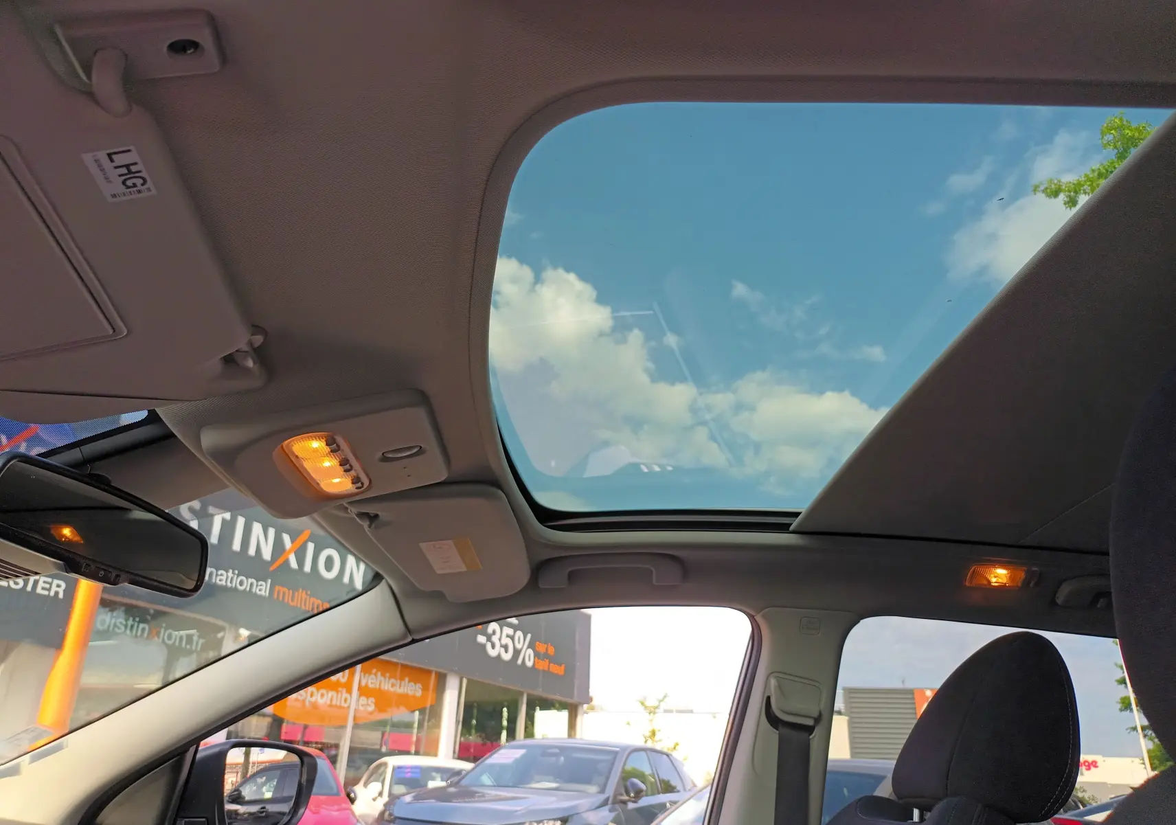 Vue intérieure du toit ouvrant panoramique du Nissan Qashqai blanc nacré 2019, avec ciel bleu visible.