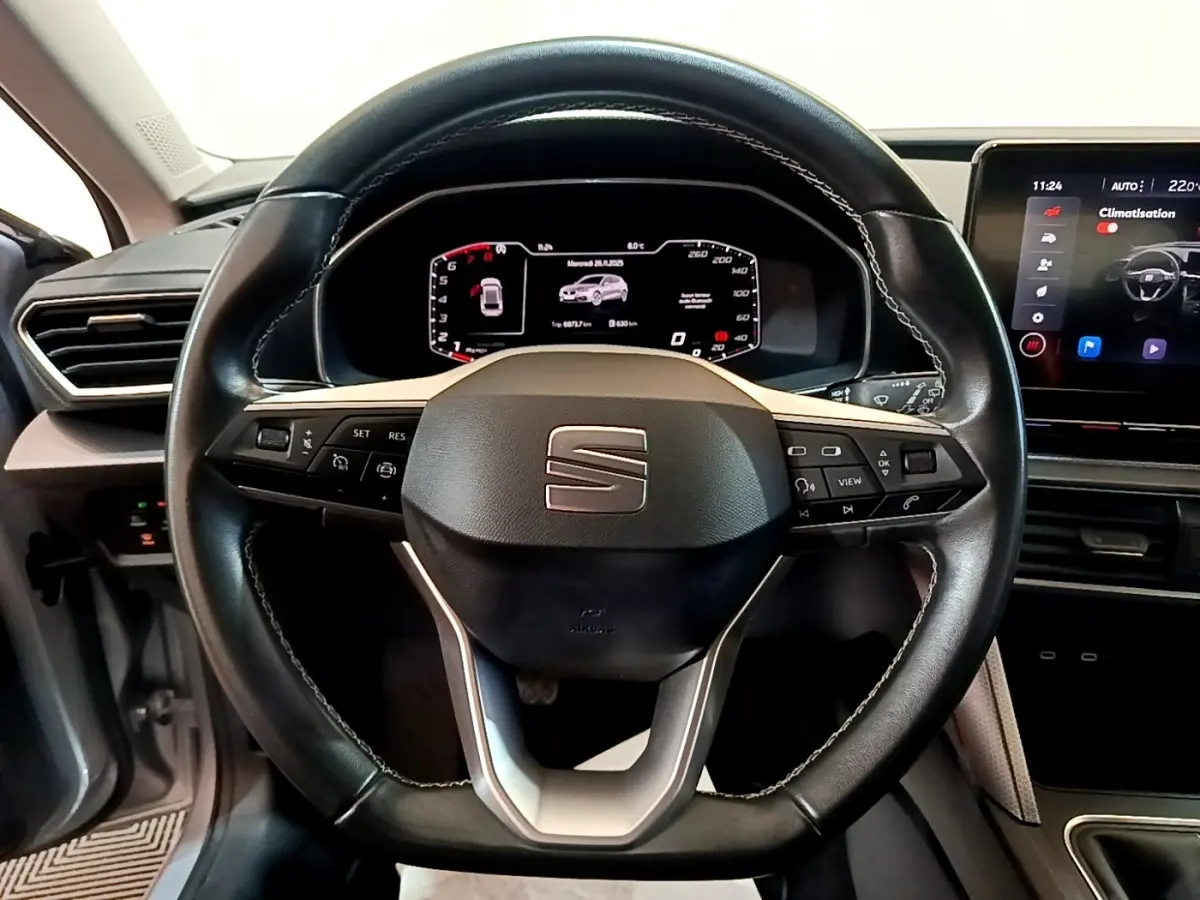 Vue rapprochée du volant cuir noir et du tableau de bord numérique du SEAT Leon 2023, intérieur moderne et épuré.