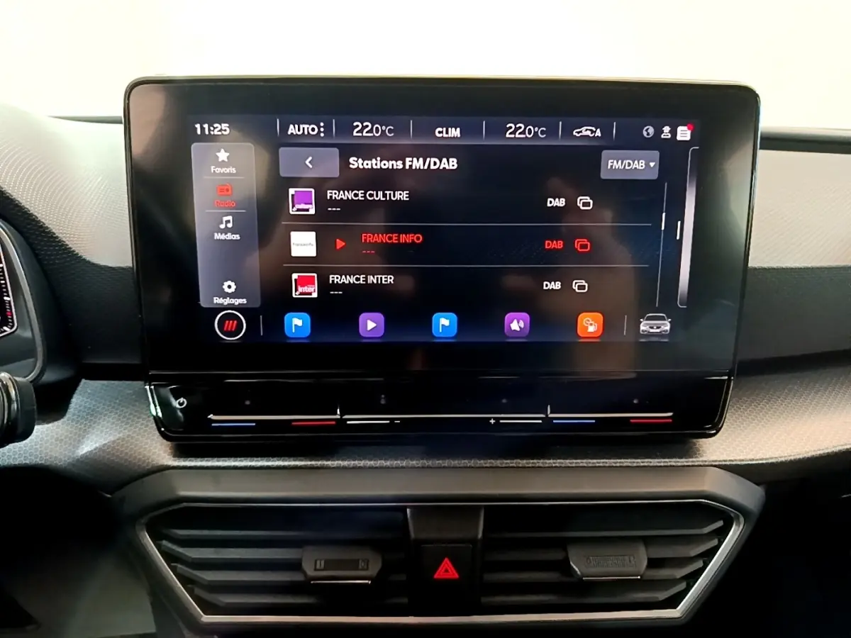 Écran tactile central affichant les stations FM/DAB dans l'habitacle du SEAT Leon gris foncé de 2023.