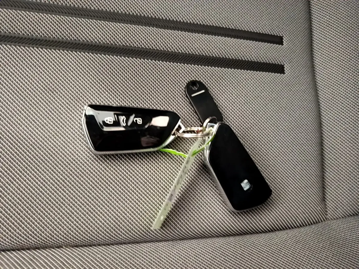 Gros plan sur une clé noire SEAT posée sur un siège gris clair en tissu à motifs fins.