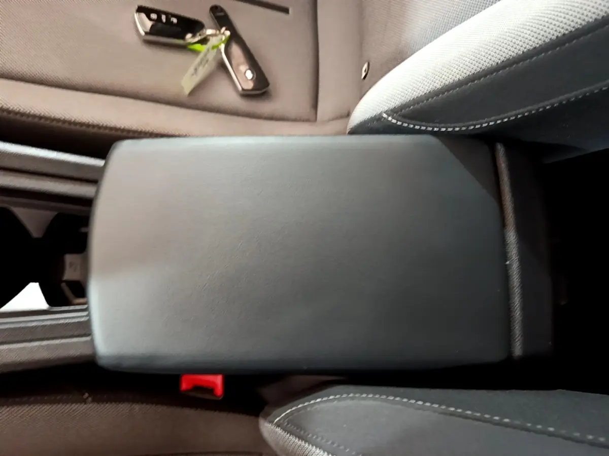 Accoudoir central noir en cuir dans l'habitacle d'une SEAT Leon gris foncé, avec clé posée sur le siège côté droit.