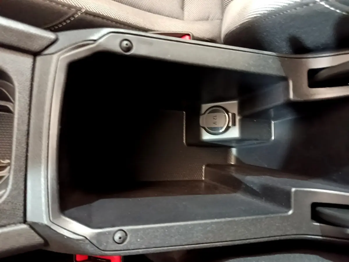 Gros plan sur la prise 12V dans le rangement central noir de la SEAT LEON 2023 version Business.