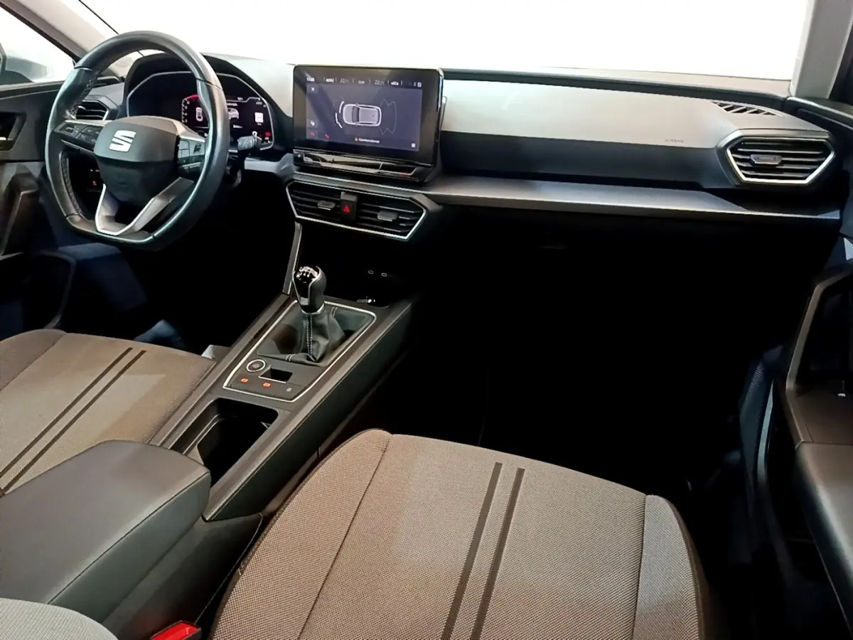 Intérieur SEAT Leon 2023 vu côté passager, tableau de bord noir avec écran tactile et levier de vitesse manuel.