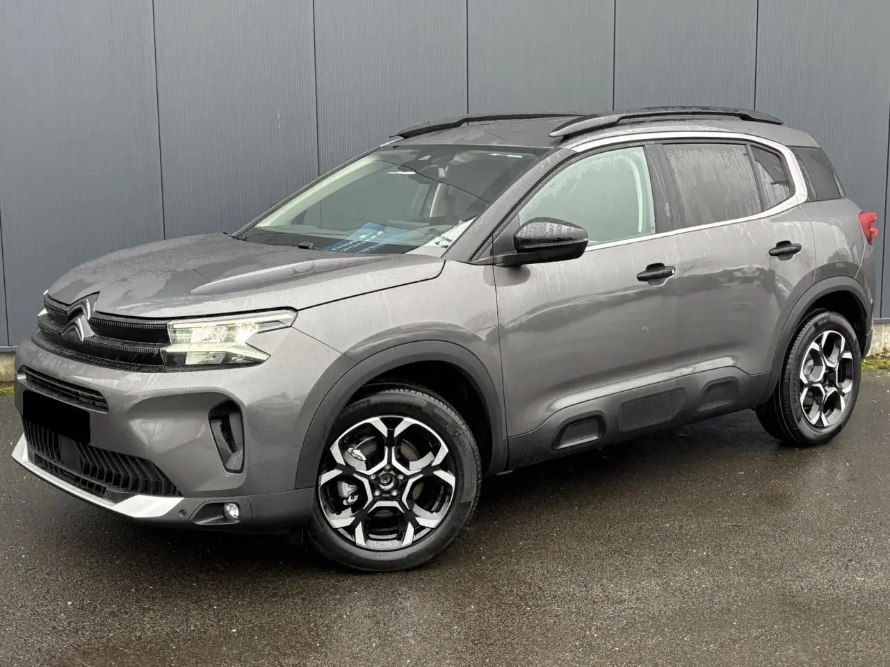 Citroën C5 Aircross gris Platinium vue 3/4 avant droit, avec jantes alliage bi-ton et barres de toit noires.